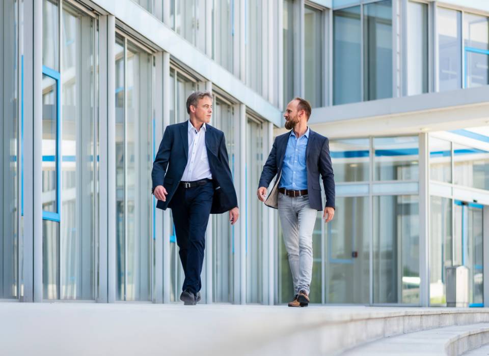 Two business men walking in a glass lobby