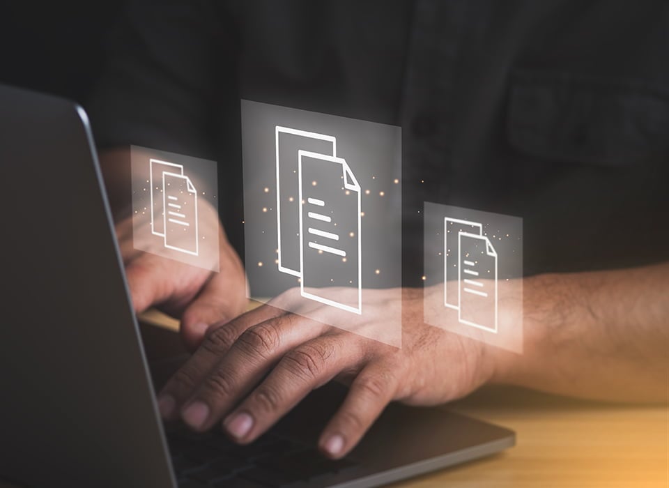 Close-up of hands typing on a laptop keyboard with digital document icons hovering above the screen—representing easy access to online forms and paperless account management.