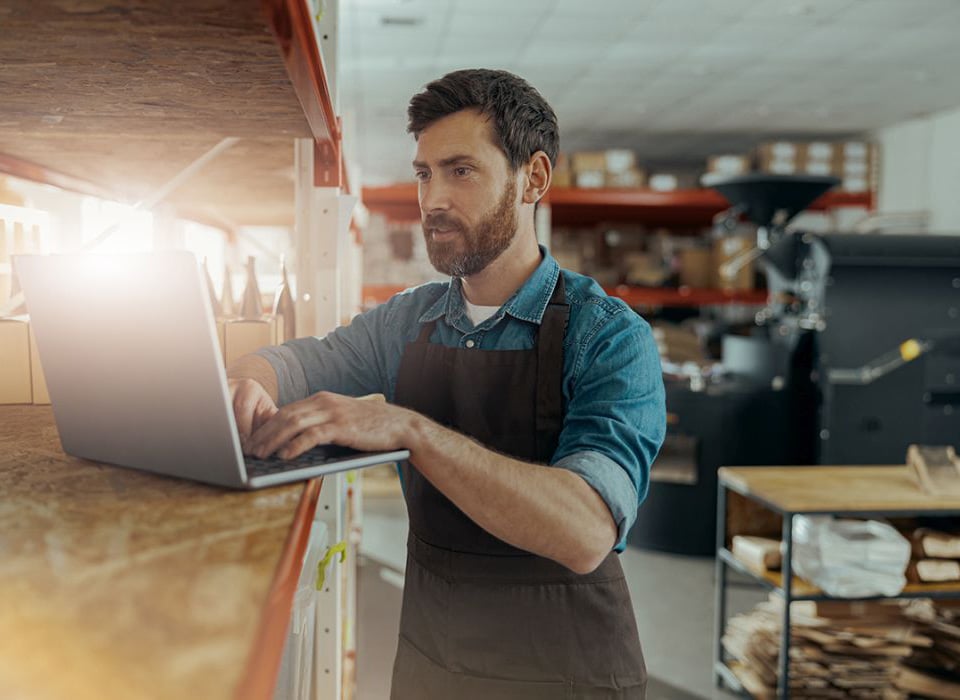 Small business owner managing operations on a laptop, symbolizing streamlined cash management solutions.