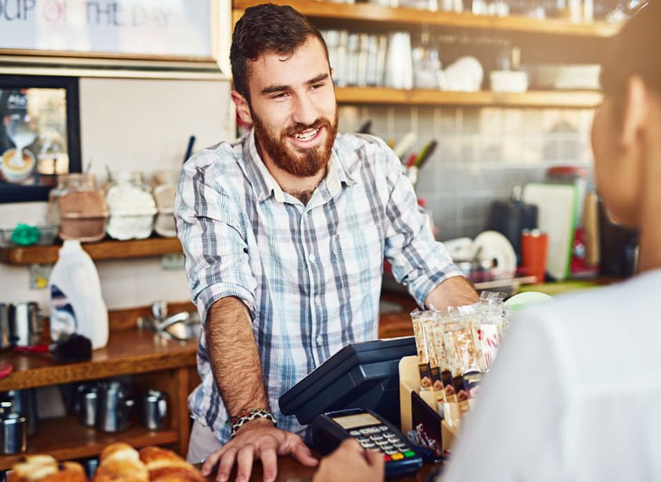 Friendly barista chatting with a customer at the counter of a cozy café.