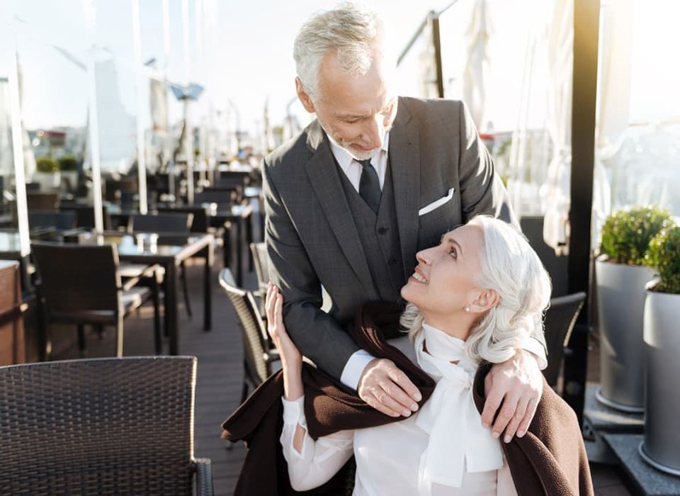 Stylish older couple sharing a warm moment at an outdoor café or restaurant.